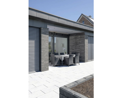 Terras met tuinmeubelen, stenen vloer en modern huis op de achtergrond