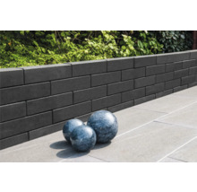 Muur van betonstenen met drie decoratieve bollen op stenen tegels