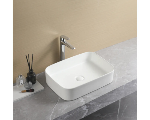 Rechthoekige keramische opzetwastafel met kraan op een wastafelblad