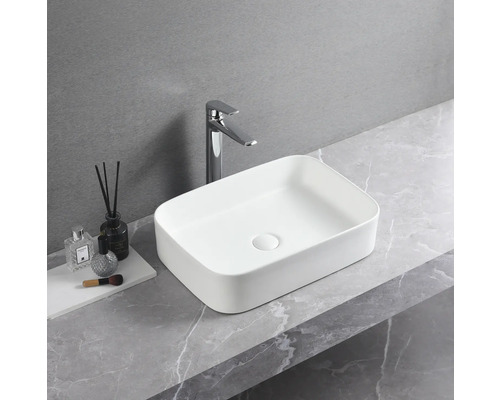 Rechthoekige keramische opzetwastafel met kraan op een werkblad