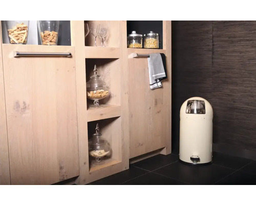 Interieurfoto van een kamer met houten kast, glazen potten met eten, handdoek en pedaalemmer.