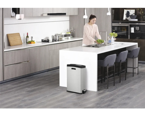 Moderne keuken met vrouw bij de gootsteen en roestvrijstalen pedaalemmer