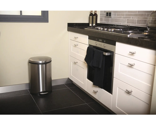 Keukenopstelling met roestvrijstalen pedaalemmer, oven en witte keukenkasten