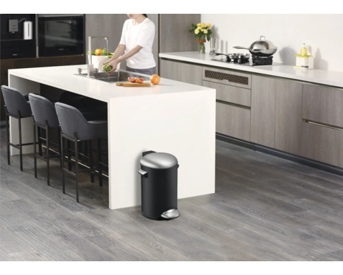 Moderne keuken met kookeiland, barkrukken en een zwarte pedaalemmer.