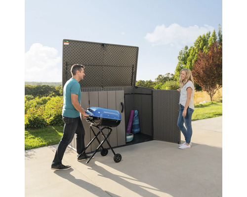 Ruime tuinkast met man die barbecue erin zet en vrouw die ernaast staat