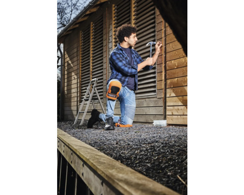 Ambachtsman met kniebeschermers timmert houten schuur