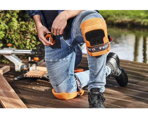 Man met kniebeschermers en meetlint bij houtbewerking