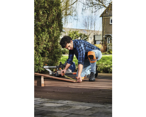 Een man meet een houten plank met een meetlint voor een afkortzaag in de buitenlucht.