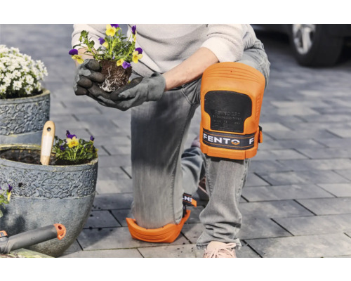 Persoon met kniebeschermers plant bloemen in een pot