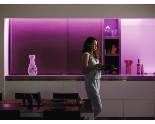 Moderne keuken met schappen en een vrouw die vaat draagt, verlicht met decoratieve verlichting