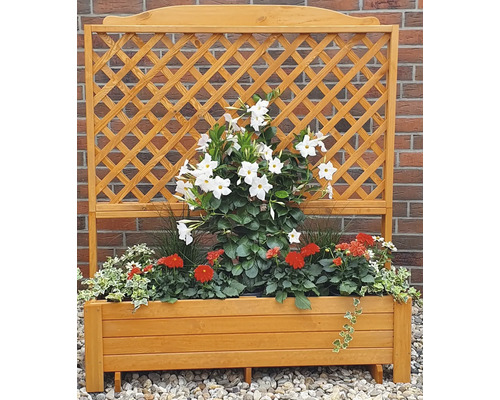 Houten bloembak met klimrek en beplanting voor een bakstenen muur