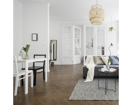 Lichte woonkamer met eettafel, bank en openslaande deuren.