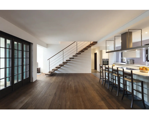 Open woonkamer met houten trap, houten vloer, kookeiland en terrasdeur.