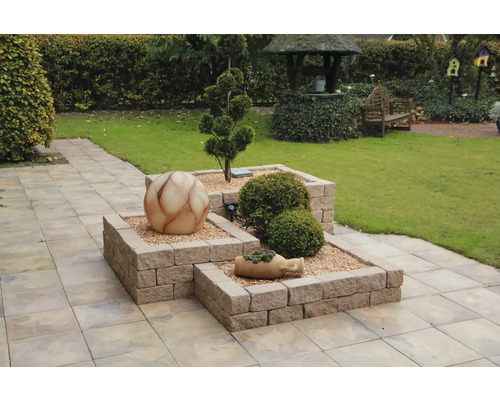 Tuinscene met verhoogde bloembedden van bakstenen, decoratieve bol en beplanting