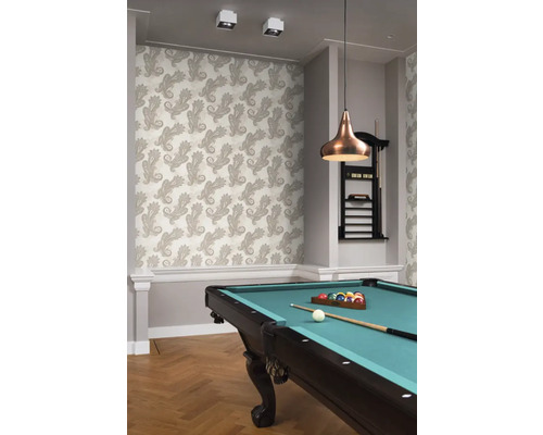 Een kamer met een patroonbehang, een biljarttafel en een hanglamp.