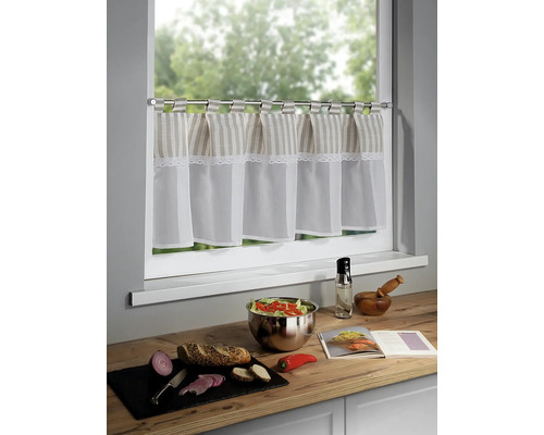 Keukenscène met café gordijn, slakom, brood, groenten en kookboek op een aanrecht voor een raam.