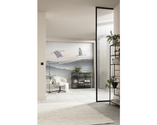 Lichte ruimte met fauteuil, rek, decoratie en fotobehang met kraanvogelmotieven.