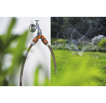 Tuinscene met waterkraan, verdeler en tuinslangen voor irrigatie