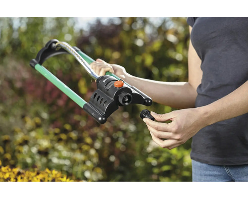 Vrouw monteert een gazonsproeier in de tuin