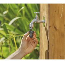Hand sluit slangconnector aan op waterkraan