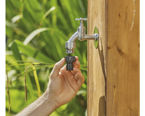 Hand sluit slangconnector aan op waterkraan