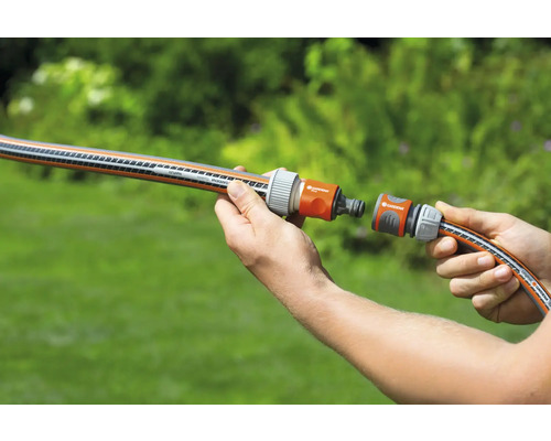 Een persoon verbindt twee tuinslangen met een koppelstuk.