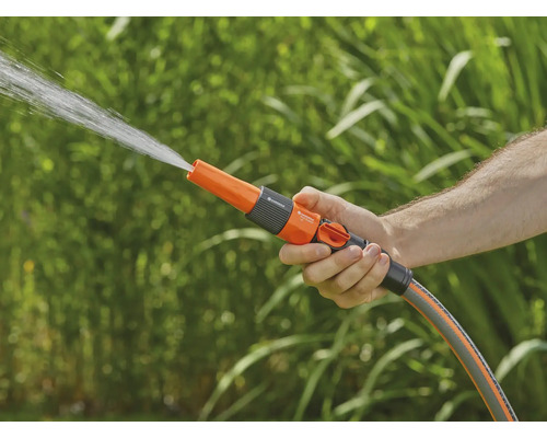 Een hand houdt een tuinsproeier vast waar water uit spuit.
