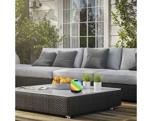 Terrasscène met bank, salontafel, fruitschaal, potplanten en een tafellamp met kleurverandering.