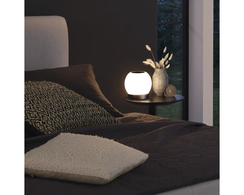 Sfeervolle slaapkameropstelling met nachtlamp, vaas en kussens op het bed