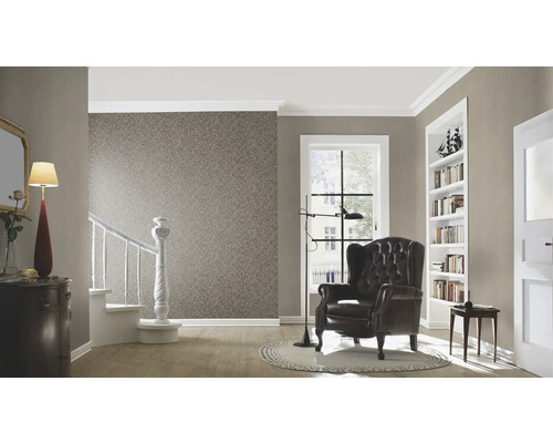 Woonkamer met behang, fauteuil, trap en decoratieve elementen voor een gezellige sfeer