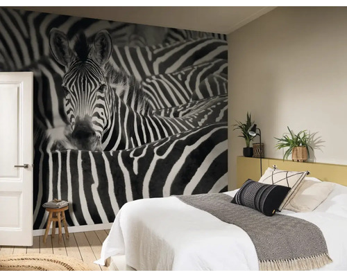 Slaapkamer met een foto van een zebra op fotobehang, bed en houten kruk.