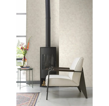 Woonkamer met kachel, stoel, tafel en behang met patroon.