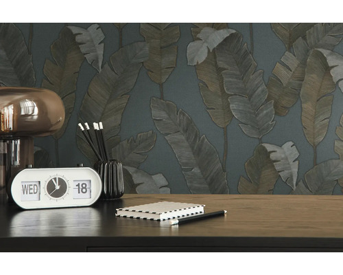 Close-up van een tafel met een klok, een notitieboek en behang met bladerpatroon