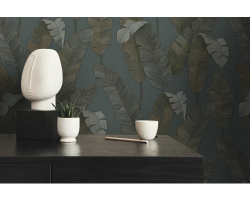 Decoratieve scène met een abstracte hoofdsculptuur, een potplant, een potlood en een kom tegen een achtergrond van behang met bladerenpatroon