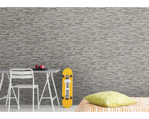 Woonkamer met stenen behang, bureau, stoel, skateboard en bed