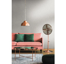 Woonkamer met roze bank, groene kussens, koperen lamp, koperen ventilator en salontafel