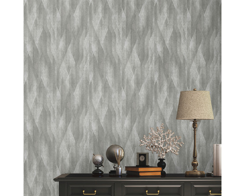 Scene met grijs vliesbehang met geometrisch patroon op een wand boven een dressoir.