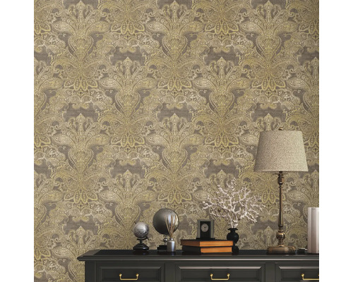 Close-up van een muur met bloemenbehang boven een zwarte commode, versierd met decoraties en een lamp.