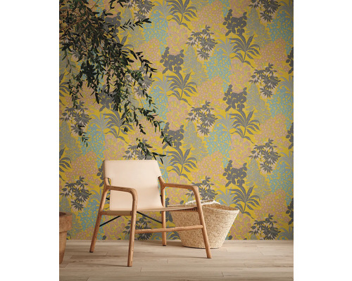 Decoratief behang met bloemmotief, gecombineerd met een fauteuil en een mand voor een gezellige sfeer in de kamer.