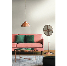 Woonkamer met roze bank, groene kussens, koperkleurige tafel, staande lamp en hanglamp.