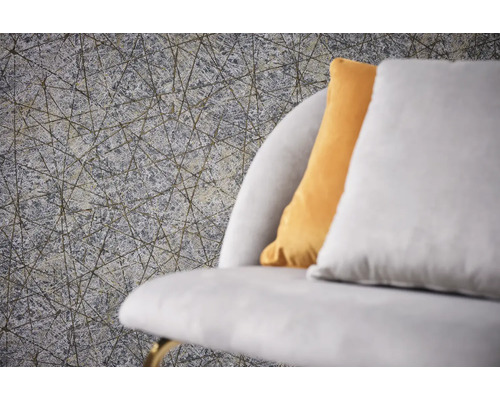 Close-up van een grijs structuurbehang met een geometrisch lijnpatroon naast een bank met kussens