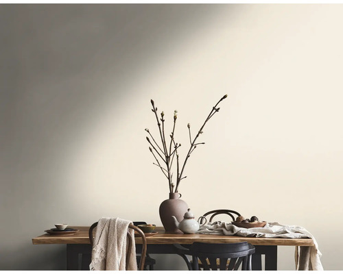 Eetkamer met houten tafel, servies en takken in een vaas voor een geschilderde muur