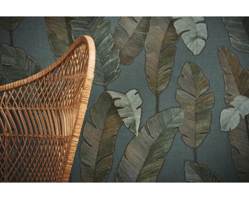 Detailopname van een behang met bladerpatroon naast een rotan stoel
