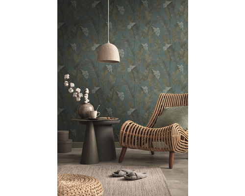 Woonkamer met behang met bladerenpatroon, rotan stoel, bijzettafel en textiellamp voor een gezellige sfeer