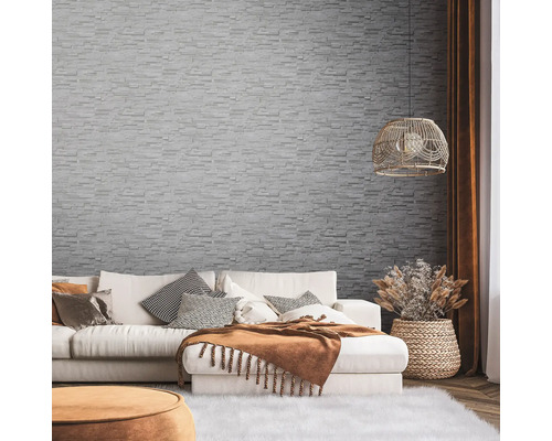 Woonkamer met bank, sierkussens en wandbekleding met steenmotief.