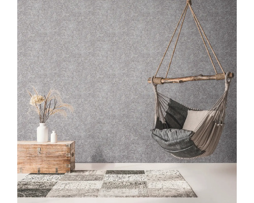 Hangstoel met kussens, houten kist met decoratie en tapijt in een heldere ruimte.