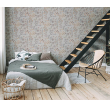 Slaapkamer met bloemmotief behang, bed, ladder en rotan stoel