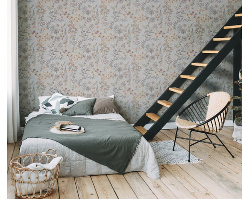 Slaapkamer met bloemmotief behang, bed, ladder en rotan stoel