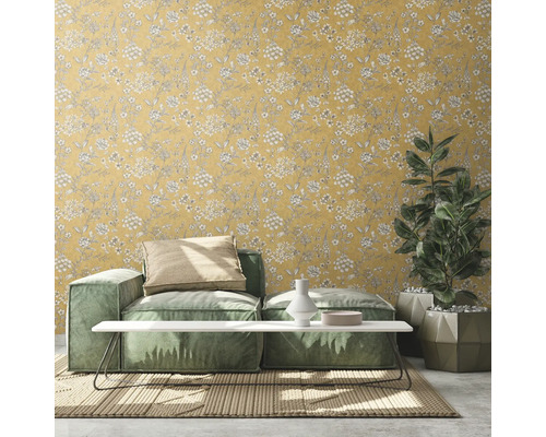 Woonkamer met geel bloemenbehang, bank, tafel en kamerplant