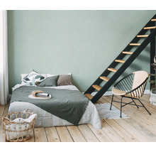 Lichte slaapkamer met bed, ladder, stoel en wasmand op houten vloer